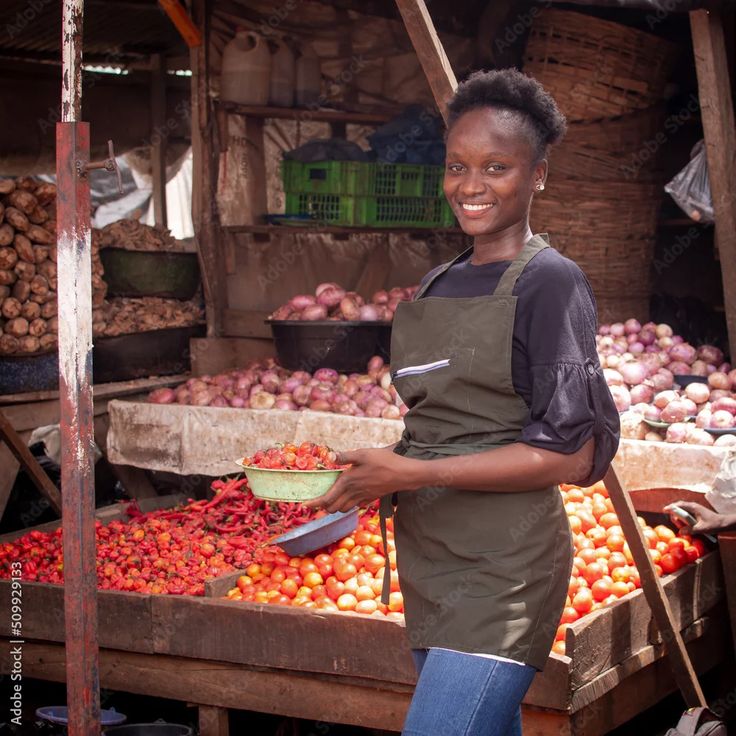 a beautiful and happy african nigerian female trader, seller, business woman or shop owner preparing to sell goods to her customers in a market stock photo adobe stock